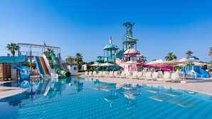 En swimmingpool med vattenrutschkanor, solstolar och en lusthus.