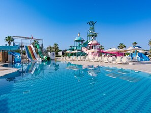 Ein Schwimmbecken mit Wasserrutschen, Liegestühlen und einem Pavillon.