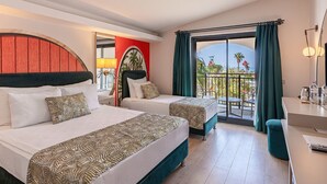 Habitación de hotel con dos camas, un balcón con vistas y un escritorio con lámpara.