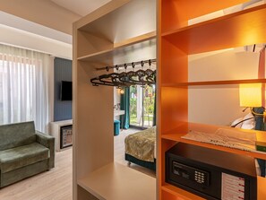 A hotel room with a sofa, a TV, a bed with a patterned bedspread, a microwave, and a laundry bag on the shelf. - La Benata Beach Hotel (Manavgat)