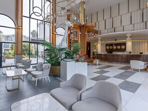 Eine geräumige Lobby mit einer Rezeption, einer Sitzecke und einer großen Pflanze.