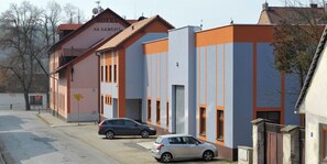 A hotel with a modern facade, two cars parked in front, and a clear sky.