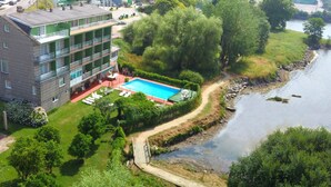 A multi-story hotel with a swimming pool and a river view. - Las Islas (Vilaboa)