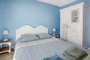 Ein Schlafzimmer mit einem Bett, einem Kleiderschrank, einem Nachttisch und einer Lampe.