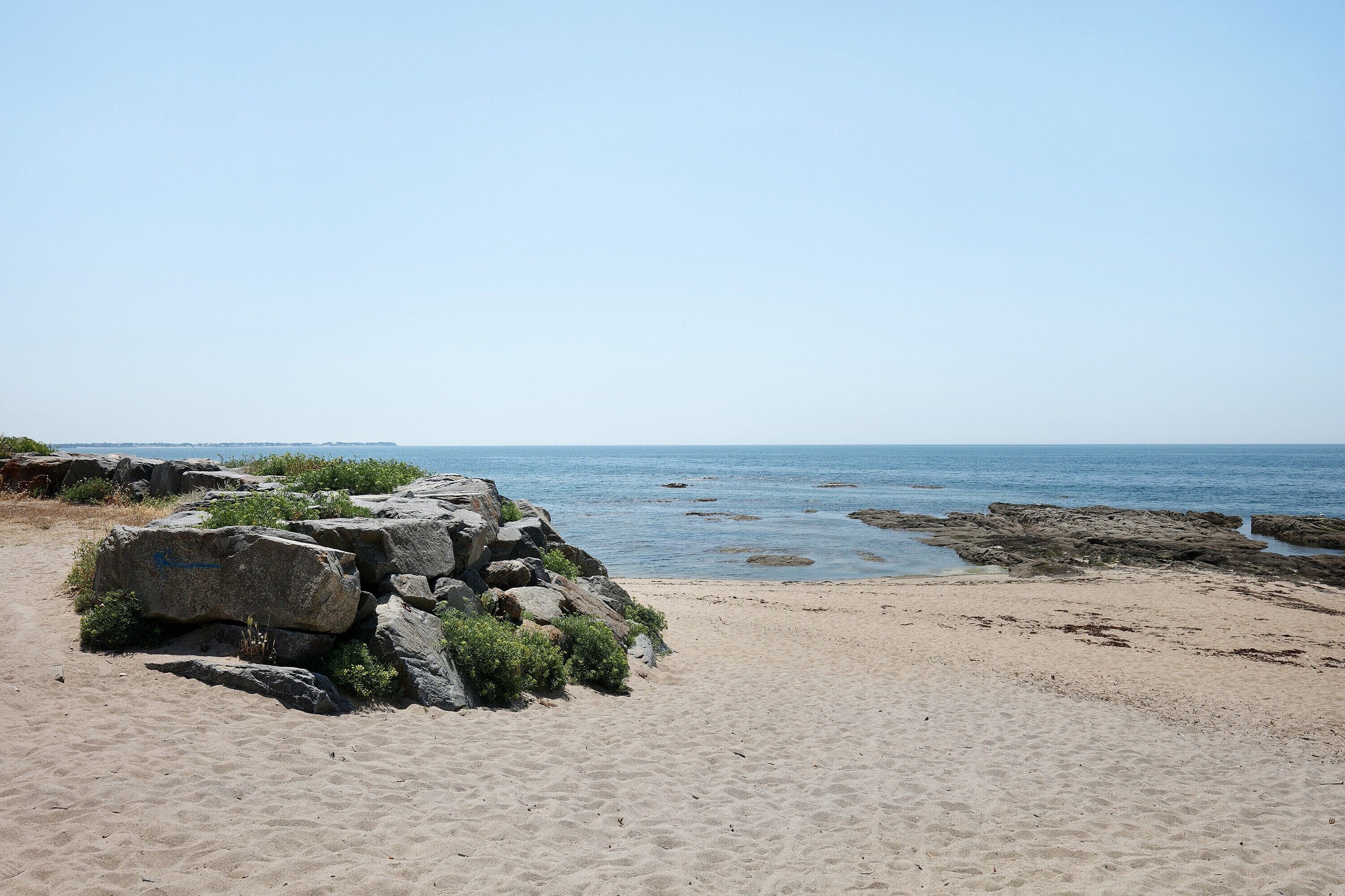 Une plage avec de gros rochers et une vue dégagée sur l’océan.
