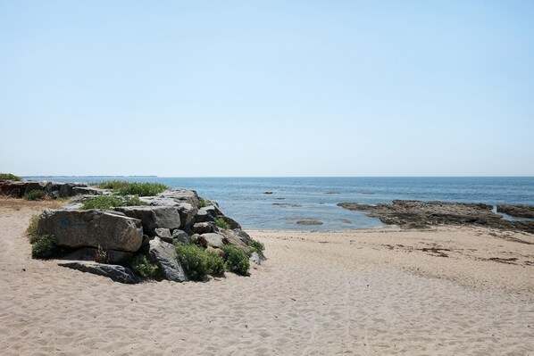 Ein Strand mit großen Felsen und freiem Blick auf das Meer.