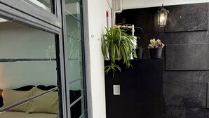 Ein Zimmer mit einem großen Fenster, einer schwarzen Tür und einem Blumentopf an der Wand.
