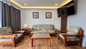 A living room with a sofa, two armchairs, a coffee table, a TV, and two framed pictures on the wall. - Spacious 4-bedroom apartment in charming Zapopan with AC (Zapopan)