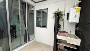 Ein Zimmer mit einer Schiebetür, einem Fenster, einem Durchlauferhitzer und einer kleinen Spüle.