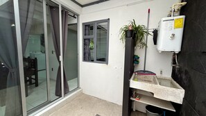 A room with a sliding glass door, a window, a water heater, and a small sink area. - Spacious 4-bedroom apartment in charming Zapopan with AC (Zapopan)