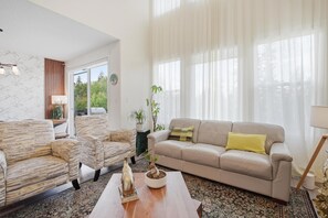 A living room with a sofa, armchairs, a coffee table, and a potted plant.