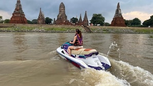 A person riding a Yamaha jet ski on a river with ancient temple structures in the background. - Ayutthaya Rive Camp And Yacht Charter (Ayutthaya)