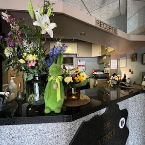 A reception area with a reception desk, a vase with flowers, and a sign that reads 'RECEPTION'. - Hotel De Venne (Genk)