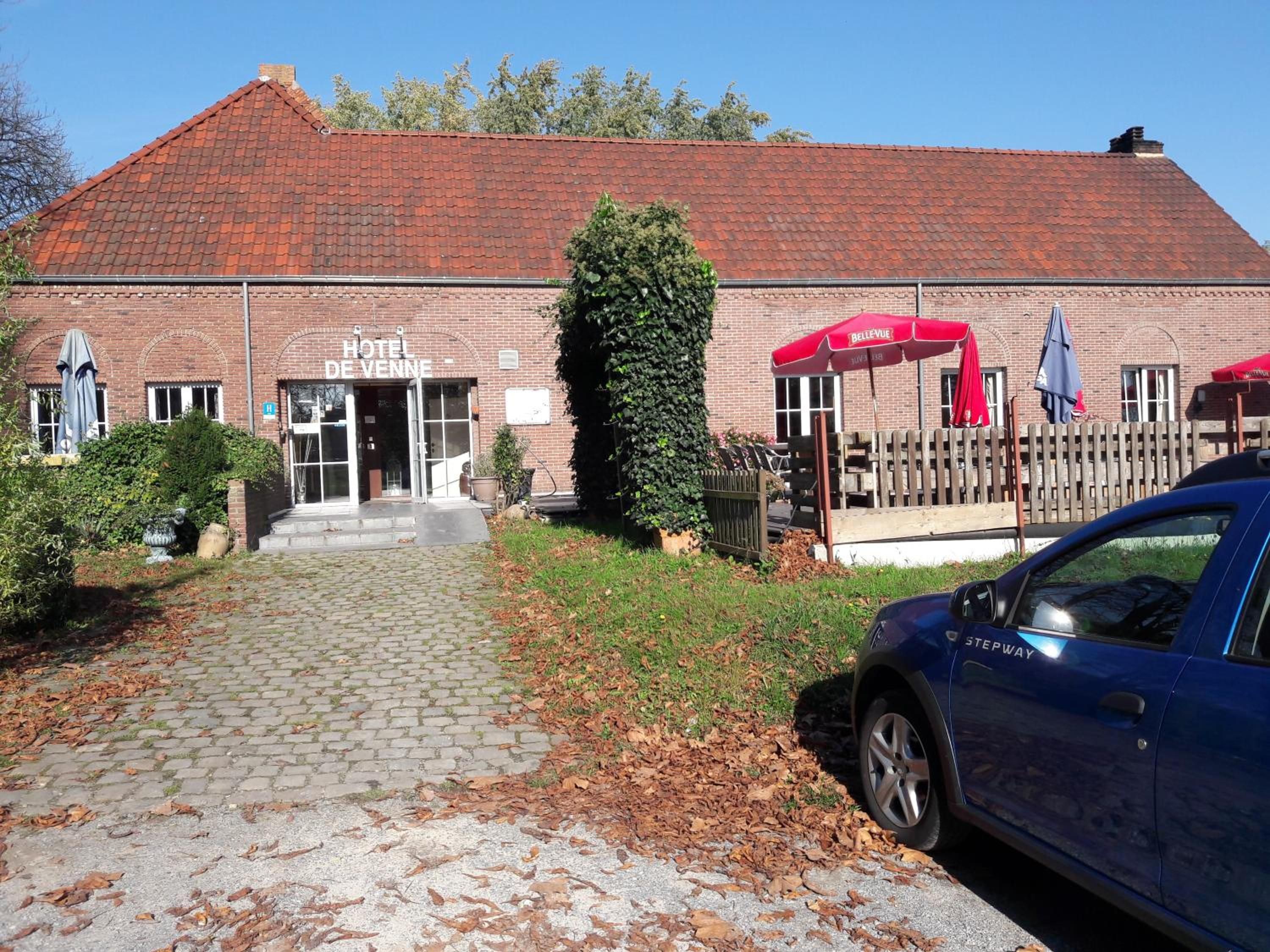 Een hotel met een rood pannendak, een bakstenen gevel en een verharde entree.