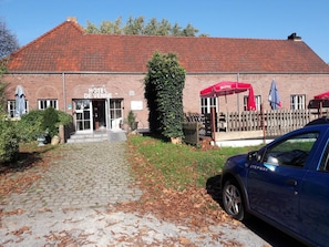A hotel with a red-tiled roof, a brick facade, and a paved entrance. - Hotel De Venne (Genk)