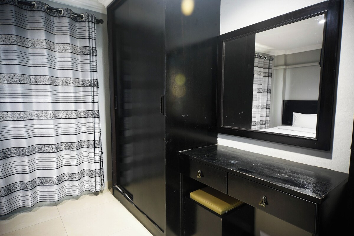 A room with a black wardrobe, a mirror, and a striped curtain.
