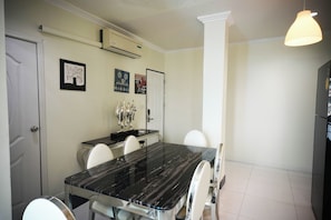 A dining area with a black marble table, white chairs, and a white ceiling. - Golden Star Pattaya By Zuzu (Pattaya)