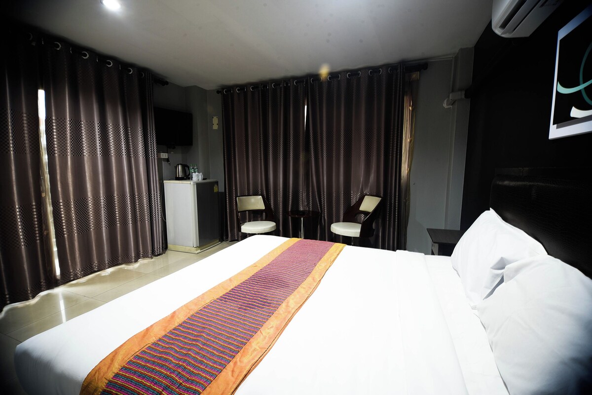 Een hotelkamer met een groot bed, een bureau met stoel en een kleine kitchenette.