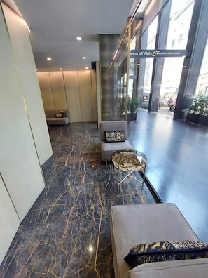 A modern lobby with a marble floor, seating areas, and large windows. - NJ Hotels & Apartments (Milan)