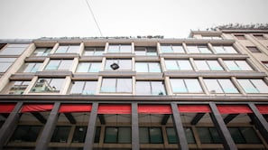 A multi-story building with a series of windows and a red awning. - NJ Hotels & Apartments (Milan)