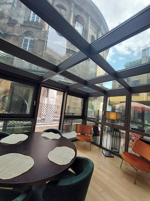 A modern indoor space with a glass ceiling, round tables, and orange chairs. - NJ Hotels & Apartments (Milan)