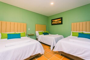 Ein Hotelzimmer mit zwei Betten, jeweils mit Kopfstütze, einem kleinen Nachttisch und einem an der Wand hängenden Bild.