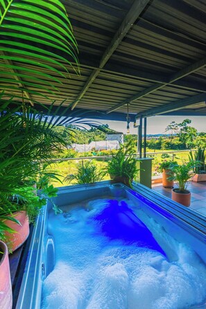 Un jacuzzi bajo una estructura cubierta, rodeado de plantas en macetas.