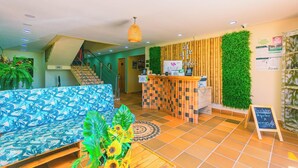 A reception area with a check-in counter, a blue sofa, a staircase, and a plant. - Bamba Hotel Guatapa (Guatapé)