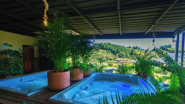 A spa area with two hot tubs, surrounded by potted plants and overlooking a scenic landscape. - Bamba Hotel Guatapa (Guatapé)