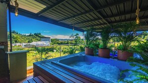 Uma banheira de hidromassagem sob um espaço coberto com vista para uma paisagem verde.