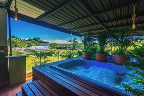 Un jacuzzi bajo una zona techada con vistas a un paisaje verde.