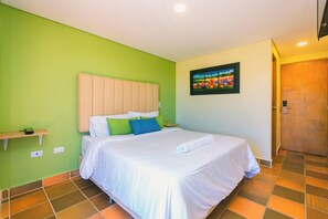 Een hotelkamer met een bed, groene wanden, een houten deur en een schilderij aan de muur.