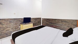 A bedroom with a bed, a dresser, and a television on a wooden wall. - Hotel O Bogor Near Taman Safari (Cisarua)