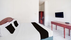 Et hotelværelse med seng, skrivebord, fjernsyn og garderobeskab.