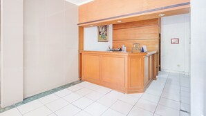 A reception area with a wooden counter, a framed picture on the wall, and a tiled floor. - Hotel O Bogor Near Taman Safari (Cisarua)