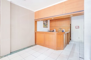 Uma área de recepção com balcão de madeira, um quadro na parede e piso de azulejos.