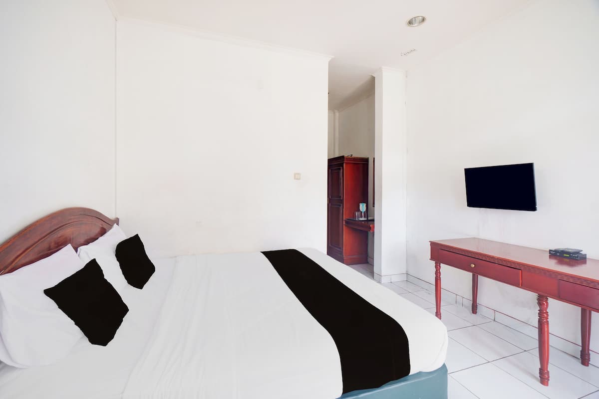 A hotel room with a bed, a desk, a television, and a wardrobe.