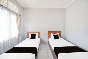 Una habitación de hotel con dos camas individuales, una ventana con cortinas y suelo de baldosas.