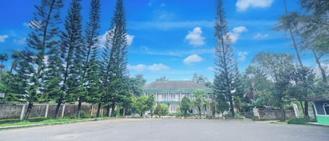 A spacious paved area with tall trees and a building in the background.