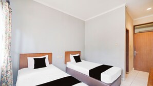A hotel room with two single beds, a wooden door, and a tiled floor. - Hotel O Bogor Near Taman Safari (Cisarua)