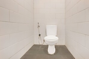 Un baño pequeño con azulejos blancos, un inodoro y una ducha.