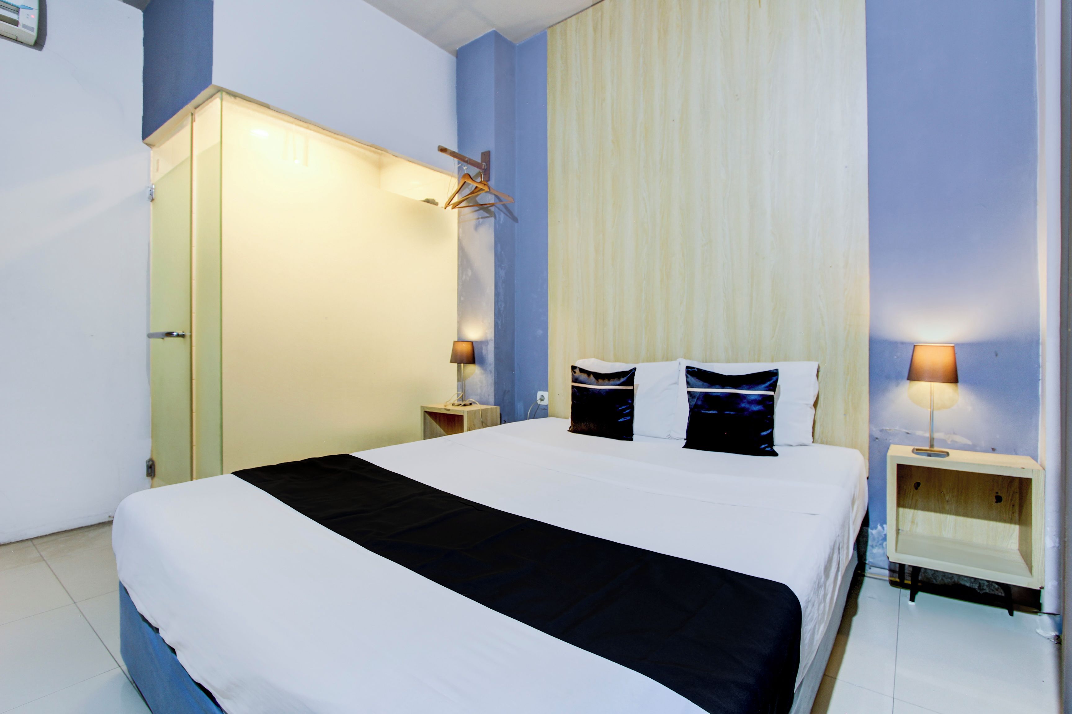 Une chambre d’hôtel comprenant un lit, des tables de chevet, une armoire et un porte-manteau.