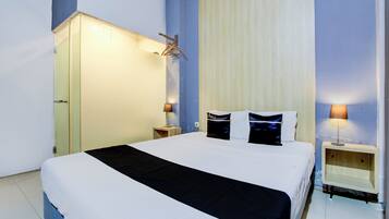 Une chambre d’hôtel comprenant un lit, des tables de chevet, une armoire et un porte-manteau.