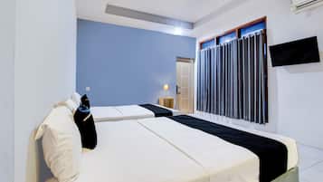 A hotel room with two beds, a flat-screen TV, and a window with curtains.