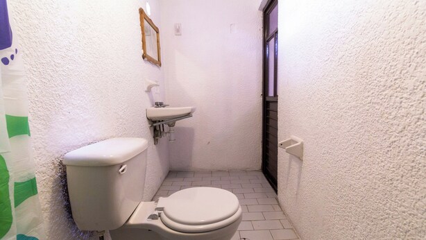 A small, narrow bathroom with a toilet, sink, and a mirror on the wall. - Hotel O Tegal Near Near Pacific Mall Tegal (Tegal)