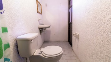 Un baño pequeño y estrecho con inodoro, lavabo y espejo en la pared.