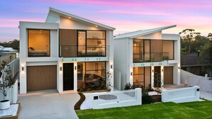 Une maison moderne à deux étages, dotée de grandes fenêtres, d’un garage fermé et d’une pelouse bien entretenue.