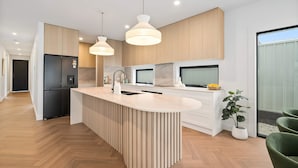Une cuisine moderne dotée d’un îlot central, de meubles en bois et de luminaires suspendus.