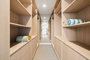 A narrow hallway with wooden shelving units on both sides, leading to a door at the end. - The Dunes on Beecroft (Huskisson)