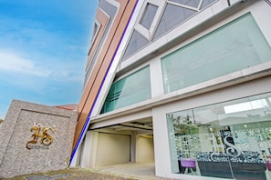 A modern building with a large glass facade, a prominent logo on the left, and a clear sky. - Townhouse Oak Near The Park Mall Semarang (Semarang)